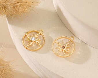 May include: Two gold-toned sun charm pendants with a clear rhinestone in the center. The charms are round and have a detailed sun design.