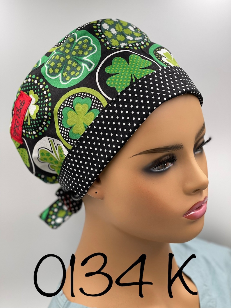 Puede incluir: Un gorro de quir&oacute;fano negro y verde con un ribete de lunares negros y blancos. El gorro tiene un patr&oacute;n de tr&eacute;bol de cuatro hojas y el texto "0134 K" est&aacute; escrito debajo del gorro.