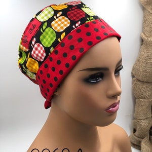 May include: A red and black polka dot scrub hat with a black and white apple print on the top. The hat has a label that says "Ebele".