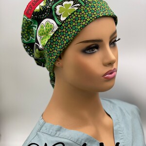 Puede incluir: Un gorro de quir&oacute;fano negro y verde con un patr&oacute;n de tr&eacute;bol. El gorro tiene una etiqueta roja que dice "Top 3 Ebele". El gorro est&aacute; en la cabeza de un maniqu&iacute;. El texto "0134 M" est&aacute; escrito en la camisa del maniqu&iacute;.