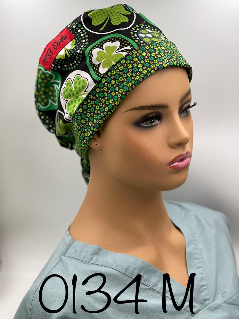 Puede incluir: Un gorro de quir&oacute;fano negro y verde con un patr&oacute;n de tr&eacute;bol. El gorro tiene una etiqueta roja que dice "Top 3 Ebele". El gorro est&aacute; en la cabeza de un maniqu&iacute;. El texto "0134 M" est&aacute; escrito en la camisa del maniqu&iacute;.