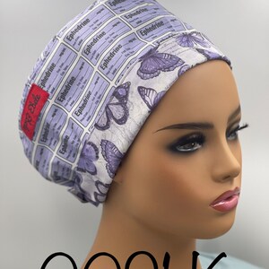 May include: A purple and white patterned surgical scrub hat with butterflies and the text "Ephedrine" repeated throughout. The hat is worn on a mannequin head.