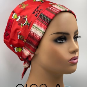 May include: Red and green surgical scrub hat with a Grinch design and the text "Naughty or Nice?"  The hat has a striped red, white, and green trim.
