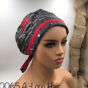 May include: Black and white patterned surgical cap with a red ribbon trim. The cap has the words "Black Lives Matter" repeated on it. The cap is tied at the back with a long tail.
