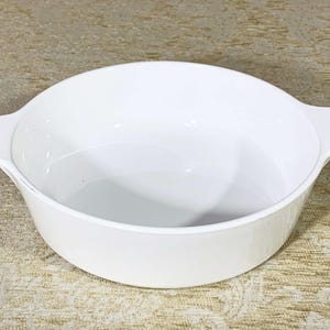 May include: White ceramic baking dish with two handles. The dish is oval shaped and has a smooth, glossy finish.