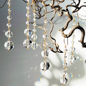 May include: Five pairs of crystal and gold dangle earrings. Each earring features a chain with multiple crystal beads.