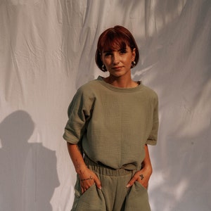 Könnte beinhalten: Eine Frau trägt ein kurzärmeliges Oberteil in Salbeigrün und eine passende Shorts. Das Oberteil hat eine lockere Passform und die Shorts haben einen Kordelzugbund.