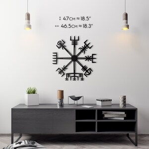 May include: Black metal Vegvisir compass wall art, approximately 18.5 inches in diameter, mounted on a white wall. The image includes a dark gray cabinet with decorative items and text indicating the size of the compass.