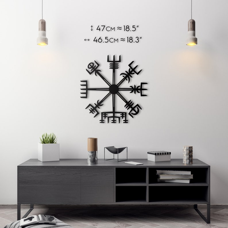May include: Black metal Vegvisir compass wall art, approximately 18.5 inches in diameter, mounted on a white wall. The image includes a dark gray cabinet with decorative items and text indicating the size of the compass.