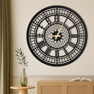 Può includere: Un grande orologio da parete rotondo nero con numeri romani e un centro decorativo. Le lancette dell'orologio sono di colore beige chiaro. L'orologio è montato su una parete di colore chiaro.