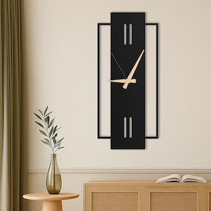 Può includere: Un orologio da parete in metallo nero con lancette dorate e una cornice rettangolare. L'orologio ha un design minimalista con due linee orizzontali sul quadrante.