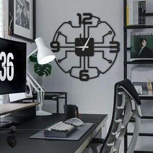 May include: Black and white clock with a circuit board design. The clock has a white background and black numbers. The clock is hanging on a white wall in a home office.