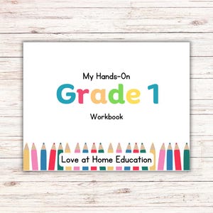 Op de afbeelding: Een wit werkboek getiteld "My Hands-On Grade 1 Workbook" met kleurrijke tekst en een rand van potloden. Het werkboek bevat de tekst "Love at Home Education" onderaan.