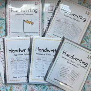 May include: A collection of spiral-bound handwriting workbooks with white covers and colorful borders. The titles include "Handwriting" and various subtopics like "Lowercase Alphabet" and "Sentences, Poetry, and Reading Comprehension." The workbooks are labeled with levels.