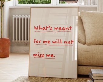 May include: A rectangular framed wall art piece featuring a white background with the red handwritten text: What's meant for me will not miss me. The frame is thin and light-colored, positioned upright on a woven rug in a bright room.