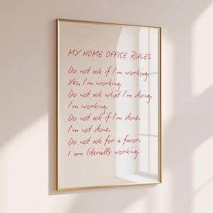 May include: A rectangular wall art print in a thin gold frame featuring red handwritten text that reads: MY HOME OFFICE RULES. Do not ask if I'm working. Yes, I'm working. Do not ask what I'm doing. I'm working. Do not ask if I'm done. I'm not done. Do not ask for a favor. I am literally working.