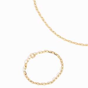 K&ouml;nnte beinhalten: Ein Set aus zwei goldenen Ketten, eine lange und eine kurze, mit einem zarten, rechteckigen Kettenmuster.