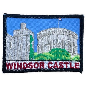 Può includere: Toppa ricamata raffigurante il Castello di Windsor. La toppa ha uno sfondo blu con una dettagliata raffigurazione del castello in tonalità di grigio e verde. Le parole "WINDSOR CASTLE" sono ricamate in rosso.