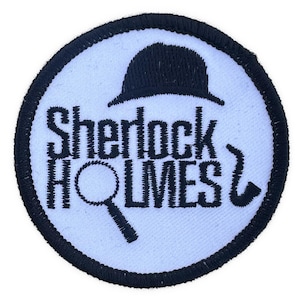 May include: Embroidered patch featuring the words "Sherlock Holmes" in black, with a magnifying glass, a pipe, and a hat. The patch is circular, with a white background and a black border.