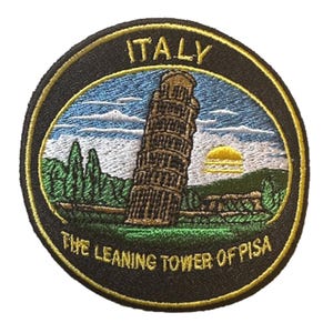 Könnte beinhalten: Runder, gestickter Aufnäher mit dem Schiefen Turm von Pisa, Italien. Der Aufnäher hat einen schwarzen Rand mit dem Wort "ITALY" oben und "THE LEANING TOWER OF PISA" unten. Das Bild zeigt einen blauen Himmel, grüne Bäume und eine gelbe Sonne.