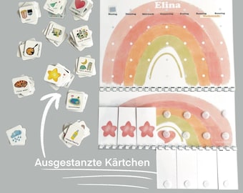 May include: A rainbow-themed chart with the name "Elina" at the top. The chart has days of the week listed across the top and spaces for stickers or other markings. There are also several small cards with various images on them, such as a star, a heart, a cloud, and a pizza slice. The text "Ausgestanzte Kärtchen" is written at the bottom of the chart.