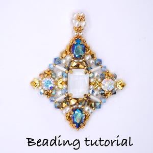 May include: A beaded pendant with a central rectangular white stone, surrounded by blue, gold, and iridescent crystals and beads. The pendant has a diamond shape with a pearl beaded top. The text "Beading tutorial" is at the bottom.