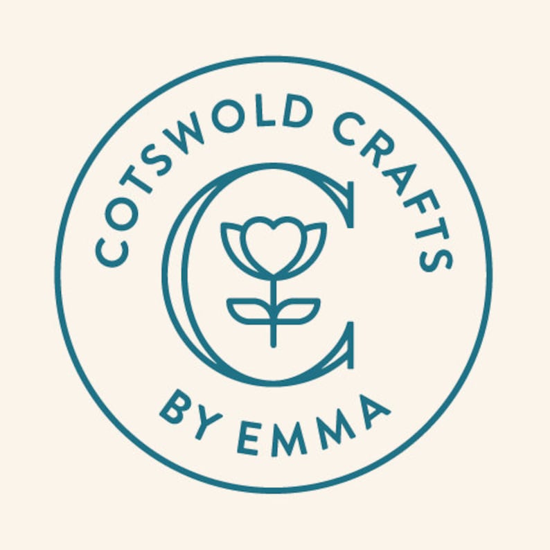 May include: Circular teal logo with the words "COTSWOLD CRAFTS" around the top and "BY EMMA" at the bottom. A teal "C" with a heart-shaped flower design is in the center. The background is a light beige color.