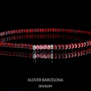 Peut inclure: Un bracelet en perles rouges avec une rangée de pierres précieuses roses et des accents argentés. KLOVER BARCELONA JEWELRY.