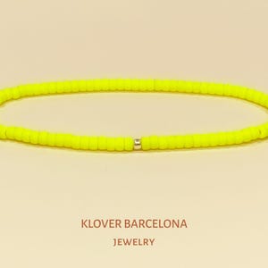 Op de afbeelding: Een neon-gele kralen armband met een zilveren kraal accent. KLOVER BARCELONA JEWELRY.