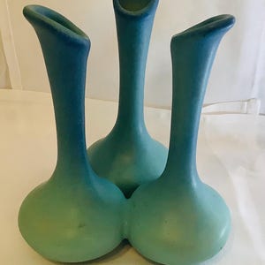 May include: Three ceramic vases in shades of blue and green. The vases have a bulbous base and a long, slender neck that flares out at the top. The color gradient transitions from a light green at the base to a deep blue at the top.