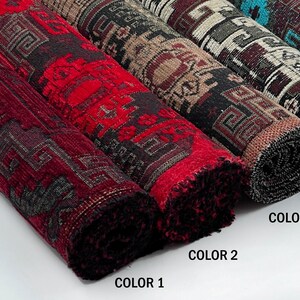 May include: Five rolled fabric bolts featuring a repeating geometric pattern. Color 1 is deep red, Color 2 is dark brown, Color 3 is black and white, Color 4 is dark maroon, and Color 5 is bright turquoise. Each bolt displays a distinct color scheme.