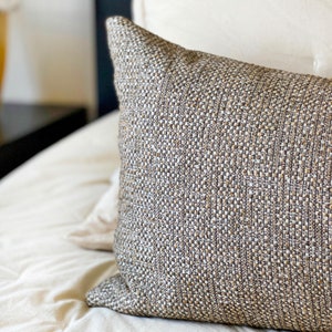 May include: A brown and beige textured throw pillow with a subtle woven pattern.