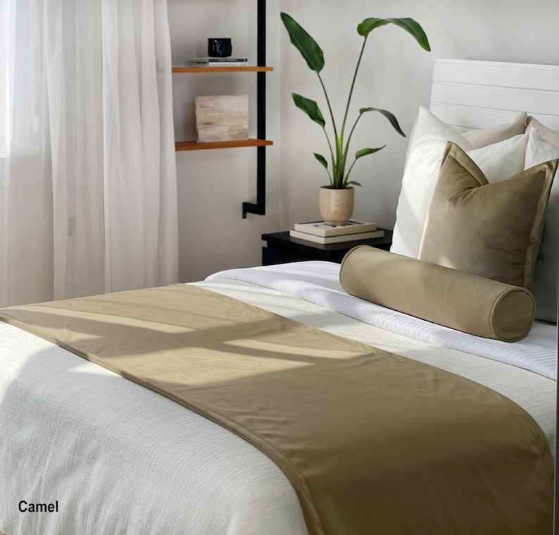 Peut inclure: Un lit avec une literie blanche, un chemin de lit couleur camel et des oreillers assortis. Un traversin cylindrique et un oreiller carr&eacute; sont sur le lit. Le mot "Camel" est dans le coin inf&eacute;rieur gauche.