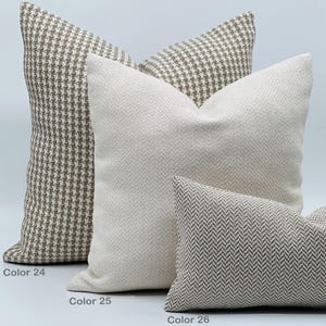 Puede incluir: Tres almohadas decorativas con diferentes patrones. La primera almohada es marr&oacute;n y blanca con un patr&oacute;n de pata de gallo. La segunda almohada es blanca con un patr&oacute;n de espiga sutil. La tercera almohada es marr&oacute;n y blanca con un patr&oacute;n de espiga.
