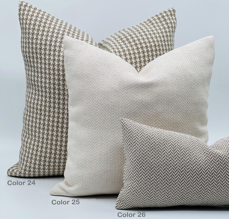 Puede incluir: Tres almohadas decorativas con diferentes patrones. La primera almohada es marr&oacute;n y blanca con un patr&oacute;n de pata de gallo. La segunda almohada es blanca con un patr&oacute;n de espiga sutil. La tercera almohada es marr&oacute;n y blanca con un patr&oacute;n de espiga.