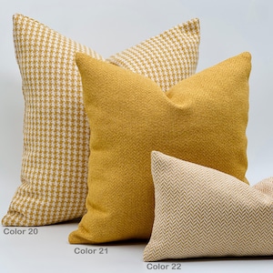 Puede incluir: Tres almohadas decorativas en varios tonos de amarillo y beige. La almohada de abajo es de color beige claro con un patr&oacute;n de espiga. La almohada del medio es de color amarillo s&oacute;lido. La almohada de arriba es de patr&oacute;n pata de gallo amarillo y blanco.