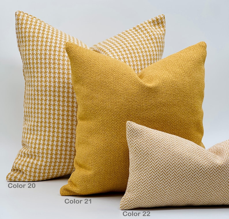 Puede incluir: Tres almohadas decorativas en varios tonos de amarillo y beige. La almohada de abajo es de color beige claro con un patr&oacute;n de espiga. La almohada del medio es de color amarillo s&oacute;lido. La almohada de arriba es de patr&oacute;n pata de gallo amarillo y blanco.