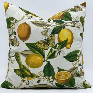 Può includere: Cuscino quadrato con sfondo bianco, con un design botanico di limoni, farfalle e un uccello. I limoni sono gialli e arancioni, con foglie verdi e fiori bianchi. Le farfalle sono gialle e marroni.