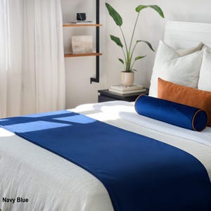 Peut inclure: Un chemin de lit bleu marine sur un lit blanc, avec un traversin bleu marine assorti et des coussins d'appoint orange. Le lit est fait de draps et d'oreillers blancs. Le texte "Navy Blue" est visible en bas &agrave; gauche.