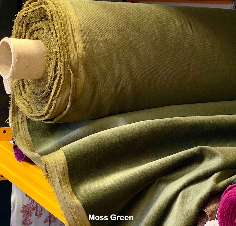 May include: A large roll of moss green fabric. The fabric is a solid color with a soft, velvety texture. The roll is mounted on a cardboard tube. The text "Moss Green" is visible at the bottom of the image.