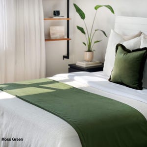 Peut inclure: Un chemin de lit vert mousse sur un lit blanc. Un oreiller vert assorti avec une bordure fonc&eacute;e repose contre des oreillers blancs. Le lit est dans une pi&egrave;ce lumineuse avec une plante et une &eacute;tag&egrave;re en arri&egrave;re-plan. Le texte "Moss Green" est en bas &agrave; gauche.