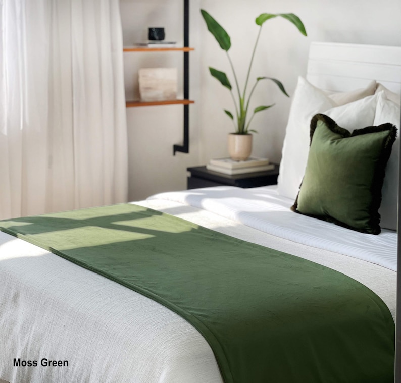 Peut inclure: Un chemin de lit vert mousse sur un lit blanc. Un oreiller vert assorti avec une bordure fonc&eacute;e repose contre des oreillers blancs. Le lit est dans une pi&egrave;ce lumineuse avec une plante et une &eacute;tag&egrave;re en arri&egrave;re-plan. Le texte "Moss Green" est en bas &agrave; gauche.