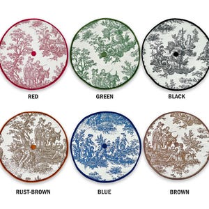 May include: Six round decorative tree skirts in various colors, each featuring a toile pattern. Colors include red, green, black, rust-brown, blue, and brown. Each skirt has a contrasting border and a central hole for the tree trunk.