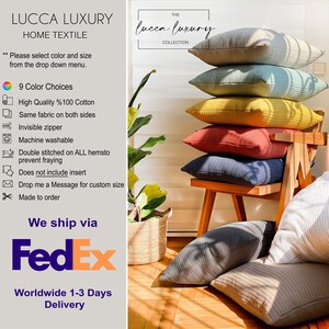 May include: A stack of five decorative throw pillows in various colours, including grey, blue, yellow, red, and navy blue, are arranged on a wooden chair. The pillows are made of a textured fabric and have a subtle sheen. The pillows are displayed in a room with a wooden floor and a potted plant in a woven basket.
