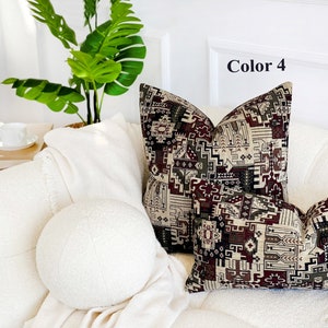 May include: Two decorative throw pillows with a geometric pattern in shades of brown, beige, and red. The pillows are on a white couch with a white round pillow in the foreground. The text "Color 4" is visible in the upper right corner of the image.