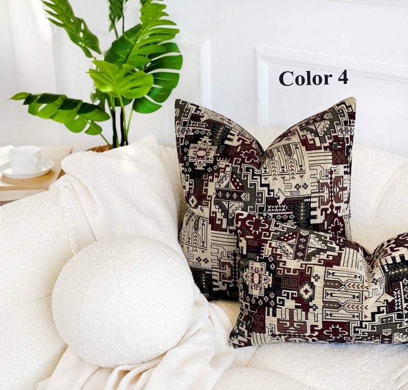 May include: Two decorative throw pillows with a geometric pattern in shades of brown, beige, and red. The pillows are on a white couch with a white round pillow in the foreground. The text "Color 4" is visible in the upper right corner of the image.