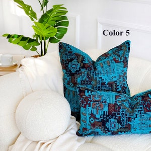 May include: Two decorative throw pillows with a geometric pattern in shades of blue, brown, and black. The pillows are on a white couch with a white round pillow in the foreground. The text "Color 5" is visible in the upper right corner of the image.