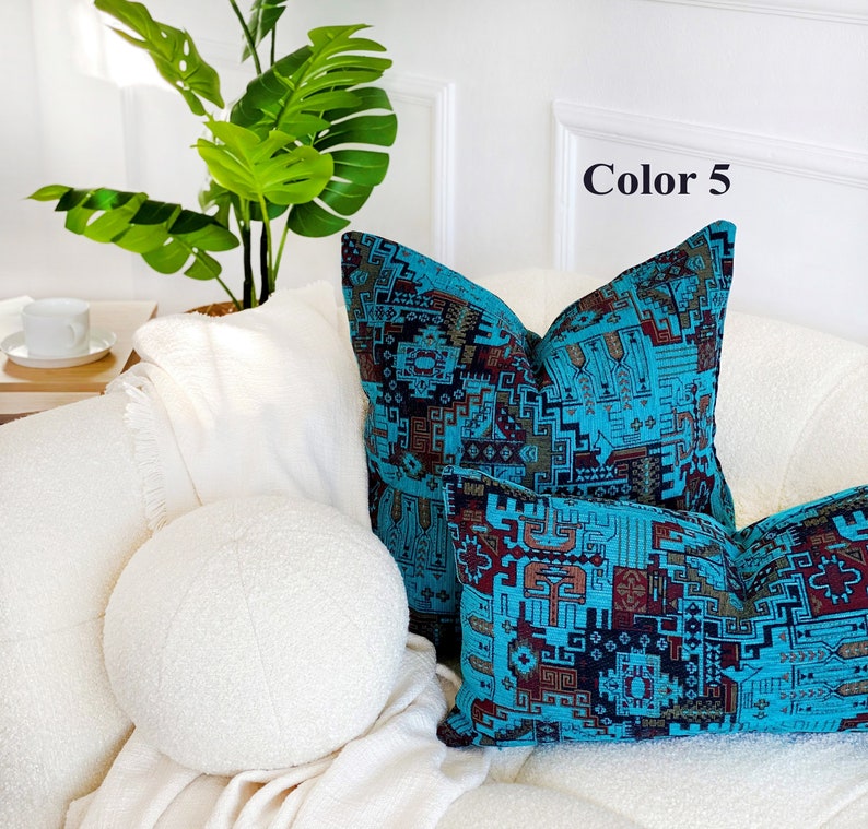 May include: Two decorative throw pillows with a geometric pattern in shades of blue, brown, and black. The pillows are on a white couch with a white round pillow in the foreground. The text "Color 5" is visible in the upper right corner of the image.
