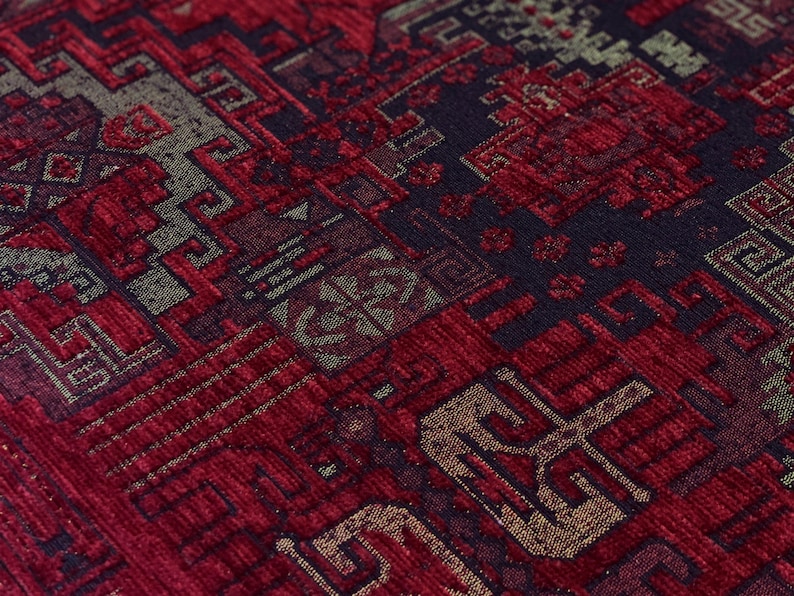 May include: A woven textile fabric featuring a dense, intricate geometric pattern in deep shades of crimson red, black, and muted gold. The surface displays a textured, multi-layered appearance with repeating angular motifs and interconnected lines.