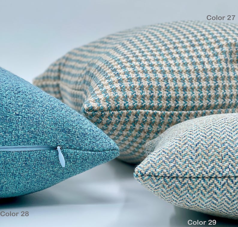 Puede incluir: Tres almohadas decorativas en varios tonos de azul y beige con diferentes patrones. La almohada de la izquierda tiene un color azul s&oacute;lido con una textura sutil. La almohada del medio tiene un patr&oacute;n a cuadros en azul y beige. La almohada de la derecha tiene un patr&oacute;n de espiga en azul y beige. Las almohadas est&aacute;n etiquetadas con los n&uacute;meros de color 28, 27 y 29.
